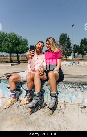 Ein verspielter junger Mann, der an sonnigen Tagen im Skateboard-Park Selfie mit seiner Freundin gemacht hat Stockfoto
