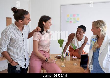 Fröhliche Kollegen, die am kreativen Arbeitsplatz diskutieren Stockfoto