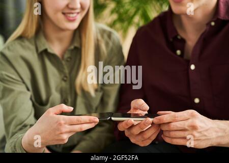 Kollegen und Kolleginnen nutzen im Büro die Ladesharing-Technologie über Smartphones Stockfoto