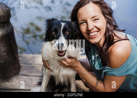 Glückliche Frau mit Border Collie auf dem Pier sitzen Stockfoto