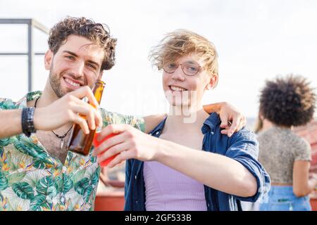 Lächelnde Freunde, die während der Party Getränke toasten Stockfoto