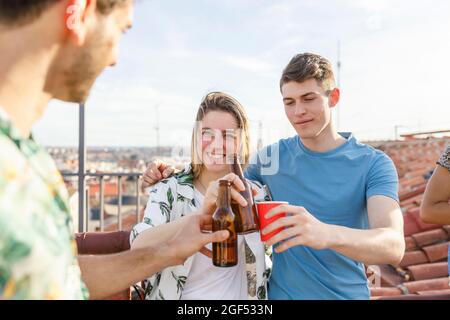 Männliche und weibliche Freunde, die während der Wochenendparty Getränke auf der Terrasse genießen Stockfoto