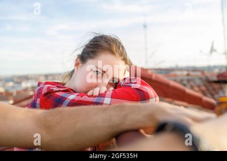 Junge Frau, die auf dem Dach auf dem Geländer gelehnt ist Stockfoto