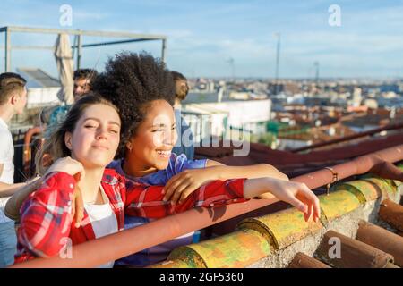 Glückliche junge mutiethnische Freundinnen auf dem Dach Stockfoto