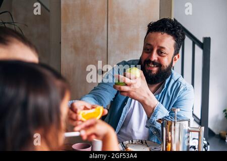 Vater gibt der Tochter Obst, während sie zu Hause sitzt Stockfoto