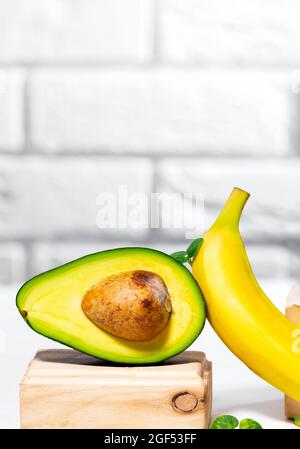 Kreative Avocado, Banane und Micro Green Balance Holzständer und Podien., weißer Hintergrund, Gleichgewicht gesunde Ernährung. Ausgewogenes Ernährungskonzept. Stockfoto