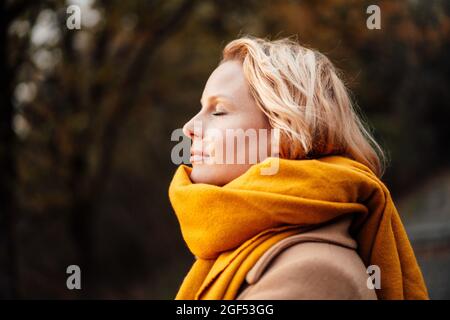 Blonde Frau mit geschlossenen Augen trägt Schal Stockfoto