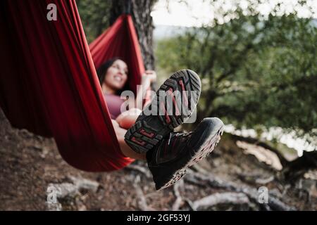 Frau, die sich während des Urlaubs in der Hängematte im Wald entspannt Stockfoto