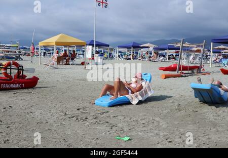 Versilia, Italien. August 2021. Der Blick auf eine Badeanstalt in der Versilia, Toskana, Italien, am 22. August 2021. Die Toskana hat mehr als 400 km (250 Meilen) Küste. Der nördliche Teil der Insel, die Versilia genannt wird, hat einen breiten und langen Sandstrand, der kilometerweit von Marina di Carrara bis Torre del Lago Puccini reicht und glamouröse Resorts wie Forte dei Marmi, Marina di Pietrasanta und Viareggio umfasst. Hunderte von Badeanstalten bedecken die Küste, mit Apuanischen Alpen, einer sehr beeindruckenden Bergkette im Hintergrund.(Elisa Gestri/Sipausa) Quelle: SIPA USA/Alamy Live News Stockfoto