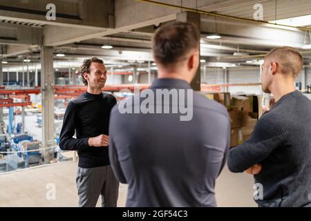 Männliche Fachleute, die in der Fabrik diskutieren Stockfoto