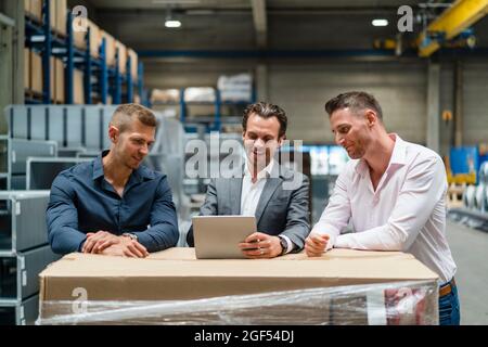 Lächelnde männliche Profis diskutieren über digitale Tablets in der Industrie Stockfoto