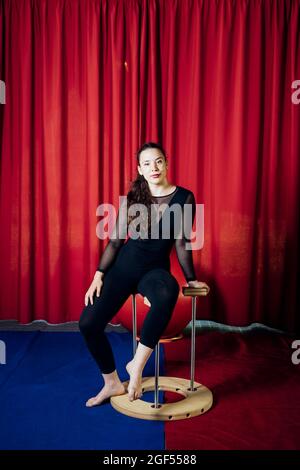 Weibliche Darstellerin, die im Zirkus auf einem Handstand sitzt Stockfoto