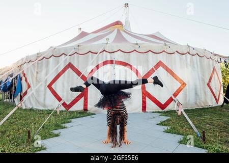 Weibliche akrobatin streckt die Beine, während sie den Handstand auf dem Fußweg macht Stockfoto