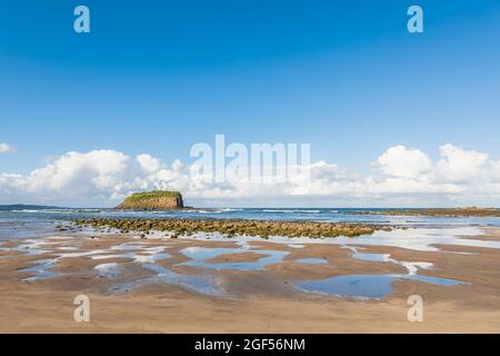 Sommerhimmel über dem Strand von Minnamurra mit Stack Island im Hintergrund Stockfoto