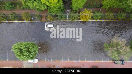 Überflutete Straße nach einem ungewöhnlichen Regenguss in den Vororten. Autos bewegen sich auf der überfluteten Straße. Folgen einer Naturkatastrophe. Stockfoto