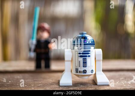 POZNAN, POLEN - 09. Aug 2021: Ein Lego Star Wars R2 D2 Spielzeugroboter im Vordergrund und ein Skywalker mit blauem Laserschwert Stockfoto