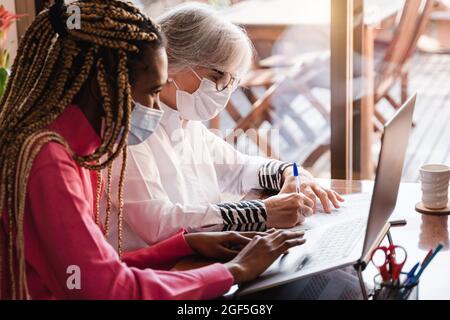 Verschiedene ältere und junge afrikanische Frauen, die während des Coronavirus-Ausbruchs am Laptop-Computer im Home Office arbeiten - konzentrieren Sie sich auf das Gesicht der alten Frau Stockfoto