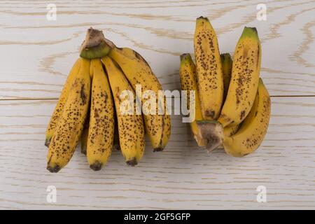 Bündel gelb sommersprossige Bananen auf einer hölzernen Textur Stockfoto