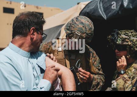 Ein Mitarbeiter der 24. Marine Expeditionary Unit (MEU) und ein Medic der 82. Airborne Division helfen einem Evakuierten während einer Evakuierung am Hamid Karzai International Airport, Kabul, Afghanistan, am 22. August. US-Dienstmitglieder unterstützen das Außenministerium bei einer nicht-kämpferischen Evakuierungsoperation (NEO) in Afghanistan. (USA Marine Corps Foto von Sgt. Isaiah Campbell) Stockfoto