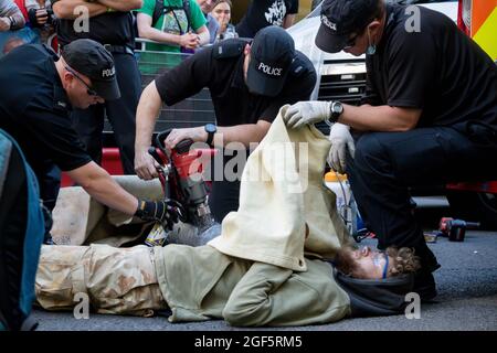 London, Großbritannien, 21. August 2021:- Spezialbeamte der Polizei verwenden Schneidausrüstung, um das Aussterben zu beseitigen Rebellion-Demonstranten aus einem Metallpip Stockfoto