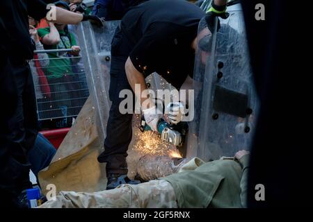 London, Großbritannien, 21. August 2021:- Spezialbeamte der Polizei verwenden Schneidausrüstung, um das Aussterben zu beseitigen Rebellion-Demonstranten aus einem Metallpip Stockfoto