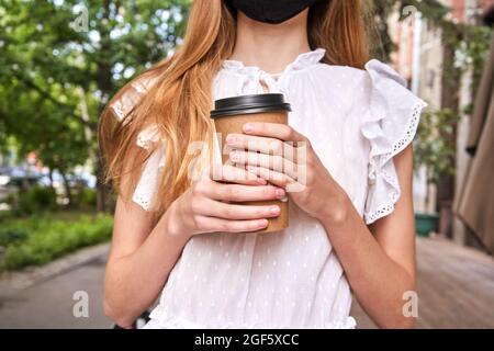 Hübsches Mädchen trinken Getränk im Freien. Kaufen Sie Kaffee zum Mitnehmen in einer Plastikbecher. Stockfoto