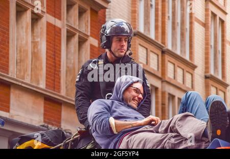 London, Großbritannien. August 2021. Ein Polizeibeamter entfernt und verhaftet einen Demonstranten, der sich während der Proteste in Covent Garden auf das Dach eines Lieferwagens steckte. Extinction Rebellion Protestierende versammelten sich im Zentrum von London zum Start ihrer zweiwöchigen Kampagne mit dem Titel Impossible Rebellion und forderten die britische Regierung auf, in der Umwelt- und Klimakrise sinnvoll zu handeln. Kredit: SOPA Images Limited/Alamy Live Nachrichten Stockfoto