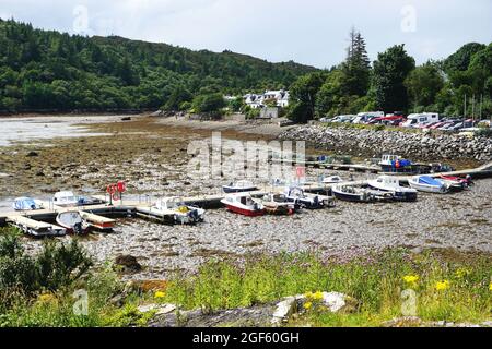 Boote und der Dock Sie sind vertäut, um bei Ebbe im Hafen im Dorf Plockton in den schottischen Highlands auf den Ebbe-Ebenen zu sitzen. Stockfoto