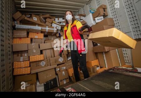 19. August 2021, Baden-Württemberg, Köngen: Adriana Tec, Dispatcher im DHL Paketzentrum in Köngen, verlädt während ihrer Nachtschicht Pakete von einem Lkw auf eine Montagelinie. (An dpa: 'Hohes Paketvolumen im DHL-Distributionszentrum - Corona oder nicht') Foto: Christoph Schmidt/dpa Stockfoto