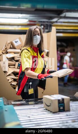 19. August 2021, Baden-Württemberg, Köngen: Adriana Tec, Dispatcher im DHL Paketzentrum in Köngen, platziert Pakete während ihrer Nachtschicht auf einer Montagelinie (an dpa: 'Hohes Paketvolumen im DHL-Versandzentrum - Corona or not') Foto: Christoph Schmidt/dpa Stockfoto