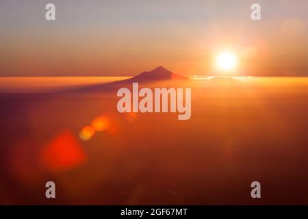 Taranaki Mount Egmont im orangen Licht des Sonnenuntergangs, vom Gipfel des Mount Ruapehu aus gesehen Stockfoto