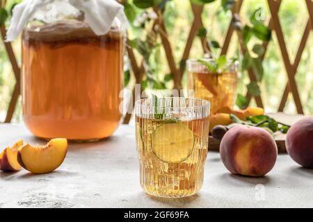 Kombucha-Tee leicht alkoholisches, leicht brausendes Getränk mit Pfirsich und Limette. Hausgemachte Gärung. Probiotisches, gut gesundes Getränk. Stockfoto