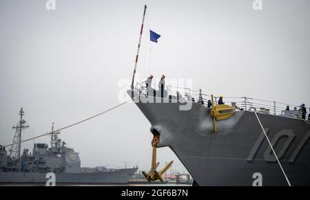 Matrosen an Bord der USS Gridley (DDG 101) heben die Navy-Bubenflagge auf den Bubenstab am Bug des Schiffes, während es am 7. Juli während der Reveille im Naval Surface Warfare Center, der Port Hueneme Division, in den Hafen einfährt. Die USS Mobile Bay (CDG 53), links, wird nach ihrer Ankunft am Vortag auf der gegenüberliegenden Seite des Hafens angedockt. Beide Schiffe befanden sich im südlichen Kriegszentrum von Kalifornien für die Veranstaltungen des Combat Systems Assessment Teams. (USA Navy Foto von Eric Parsons/veröffentlicht) Stockfoto