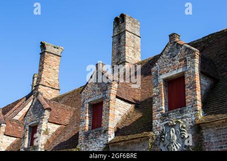 Aufnahme von Dächern im alten Stil mit Kaminen unter dem blauen Himmel in Brügge, Belgien Stockfoto