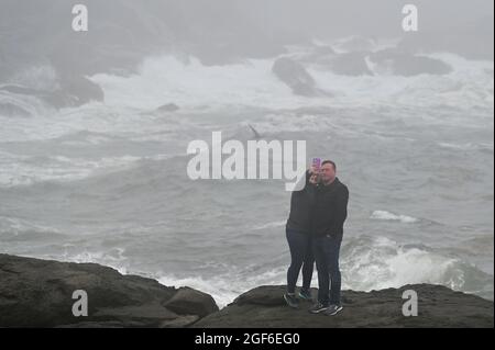 Maine, Usa. August 2021. Ein Paar fotografiert sich selbst mit krachenden Wellen gegen Felsen außerhalb des Nubble Lighthouse. (Foto von Aimee Dilger/ SOPA Images/Sipa USA) Quelle: SIPA USA/Alamy Live News Stockfoto