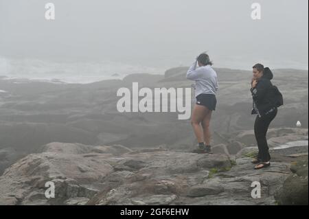 Maine, Usa. August 2021. Frauen beobachten, wie der Wind aufbläst und die Wellen am York Beach gegen die Felsen krachen. (Foto von Aimee Dilger/ SOPA Images/Sipa USA) Quelle: SIPA USA/Alamy Live News Stockfoto