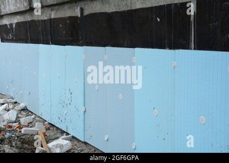 Installation von extrudierten Polystyrol-Platten oder XPS-Hartschaum-Wärmedämmung auf Teer gesprüht, um das Fundament, Keller eines Hauses zu isolieren. Stockfoto