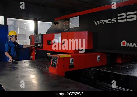 Bogor, West Java, Indonesien - Dezember 2020 : Ein Fabrikarbeiter arbeitet mit einer Stanzmaschine in einer Produktionsanlage. Stockfoto