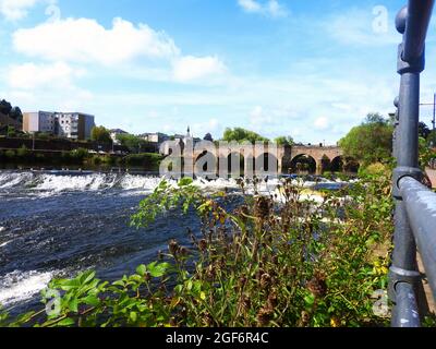 Dumfries, Schottland im August 2021 - EINE Szene, die von Whitesands aus fotografiert wurde und den Kaulquappe (oder Kaulquappe) auf der Nith unterhalb der New Bridge (erbaut 1794) zeigt. Das Maul wurde historisch mit Holzpfählen gebaut, wurde aber im Laufe der Jahre mehrfach mit Holzstämmen und Schutt rekonstruiert. Diese Szene zeigt das Wehr, das auf die gewölbte New Bridge blickt. In der Nähe (stromabwärts) befindet sich die alte Brücke oder die Devorgilla's Bridge, eine der ältesten noch in Schottland verwendeten Brücken. Die ursprüngliche Holzbrücke wurde hier um 1260 erbaut und nach Dervorguilla de Balliol, der Mutter des schottischen Königs John Balliol, benannt. Stockfoto