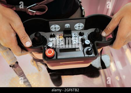 Fernbedienung eines Hubwagens in den Händen einer Person. Panel mit Joysticks und Tasten zur Steuerung des Teleskopauslegers des Krans Stockfoto