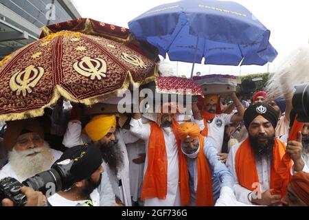 Mitglieder von Sikh riligion tragen am 24. August 2021 3 Saroops von Sri Guru Granth Sahib, der heiligen Schrift, auf dem IGI-Flughafen in Neu-Delhi, Indien. Foto von Anshuman Akash/ABACAPRESS.COM Quelle: Abaca Press/Alamy Live News Stockfoto