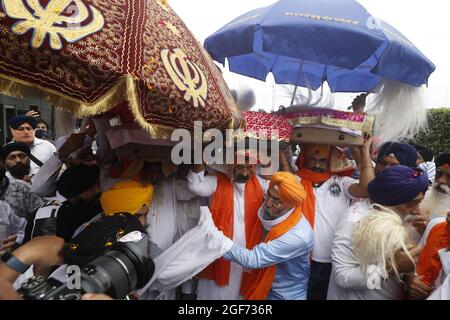 Mitglieder von Sikh riligion tragen am 24. August 2021 3 Saroops von Sri Guru Granth Sahib, der heiligen Schrift, auf dem IGI-Flughafen in Neu-Delhi, Indien. Foto von Anshuman Akash/ABACAPRESS.COM Quelle: Abaca Press/Alamy Live News Stockfoto