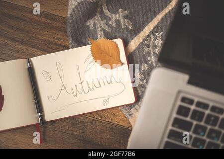 Handgeschriebenes Herbstwort mit Herbstblättern. Gemütliches Zuhause Hintergrund Stockfoto