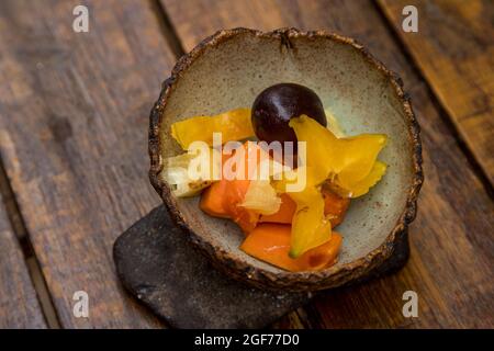Nahaufnahme von Pflaume und in Scheiben geschnittenen Mangos und Ananas in einer Schüssel auf einem Holztisch Stockfoto