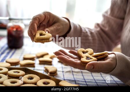 Frau, die Linzer Keks auf dem Tisch macht. Zubereitung hausgemachte traditionelle weihnachtskekse.Süßes Essen in weiblichen Händen Stockfoto