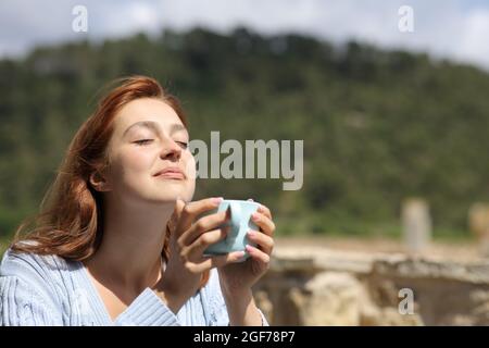 Frau, die im Freien eine Kaffeetasse in den Bergen hält Stockfoto