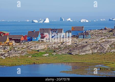 Holzhäuser und Felsen vor einer mit Eisbergen gefüllten Bucht, Disko Bay, Disko Island, Qeqertarsuaq, Arctic, Grönland, Dänemark Stockfoto