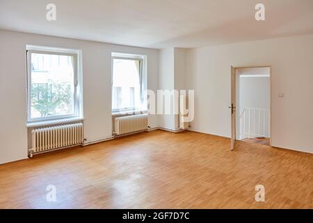 Großes, leeres weißes Zimmer in einem alten Gebäude mit Heizung, Parkett und Fenstern Stockfoto