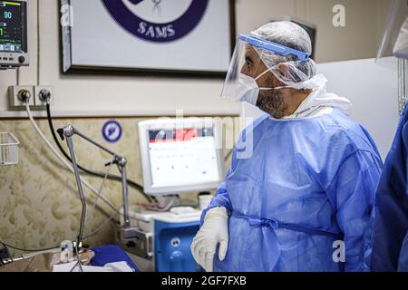 Idlib, Syrien. August 2021. Ein Arzt, der in einem Schutzanzug gekleidet ist, kümmert sich um einen älteren Mann in einem Isolationskrankenhaus in Idlib. Die Delta-Mutante kam in Idlib an, wo im Idlib-Labor für 92 Proben eine Genotypisierung durchgeführt wurde. Die Alpha-Mutante wurde in 6 Proben und die Delta-Mutante in 47 Proben gefunden, und es gibt einen signifikanten Anstieg der Anzahl der bestätigten Fälle von Covid-19 in den letzten Tagen. Kredit: SOPA Images Limited/Alamy Live Nachrichten Stockfoto