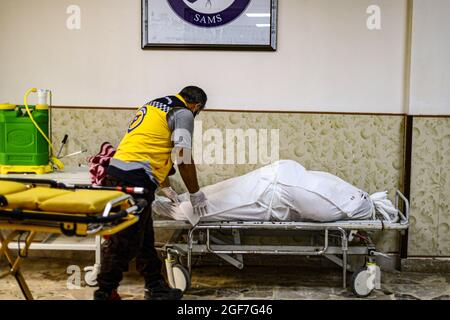Idlib, Syrien. August 2021. (ANMERKUNG DER REDAKTION: Bild zeigt den Tod) EIN Arzt, der den toten Körper einer Frau auf einer Bahre im Isolationskrankenhaus in Idlib City kleidet. Die Delta-Mutante kam in Idlib an, wo im Idlib-Labor für 92 Proben eine Genotypisierung durchgeführt wurde. Die Alpha-Mutante wurde in 6 Proben und die Delta-Mutante in 47 Proben gefunden, und es gibt einen signifikanten Anstieg der Anzahl der bestätigten Fälle von Covid-19 in den letzten Tagen. Kredit: SOPA Images Limited/Alamy Live Nachrichten Stockfoto